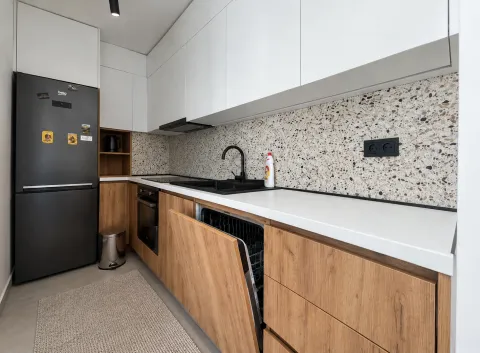 Modern kitchen with white upper cabinets, wooden fronts, and a black refrigerator. - image 3