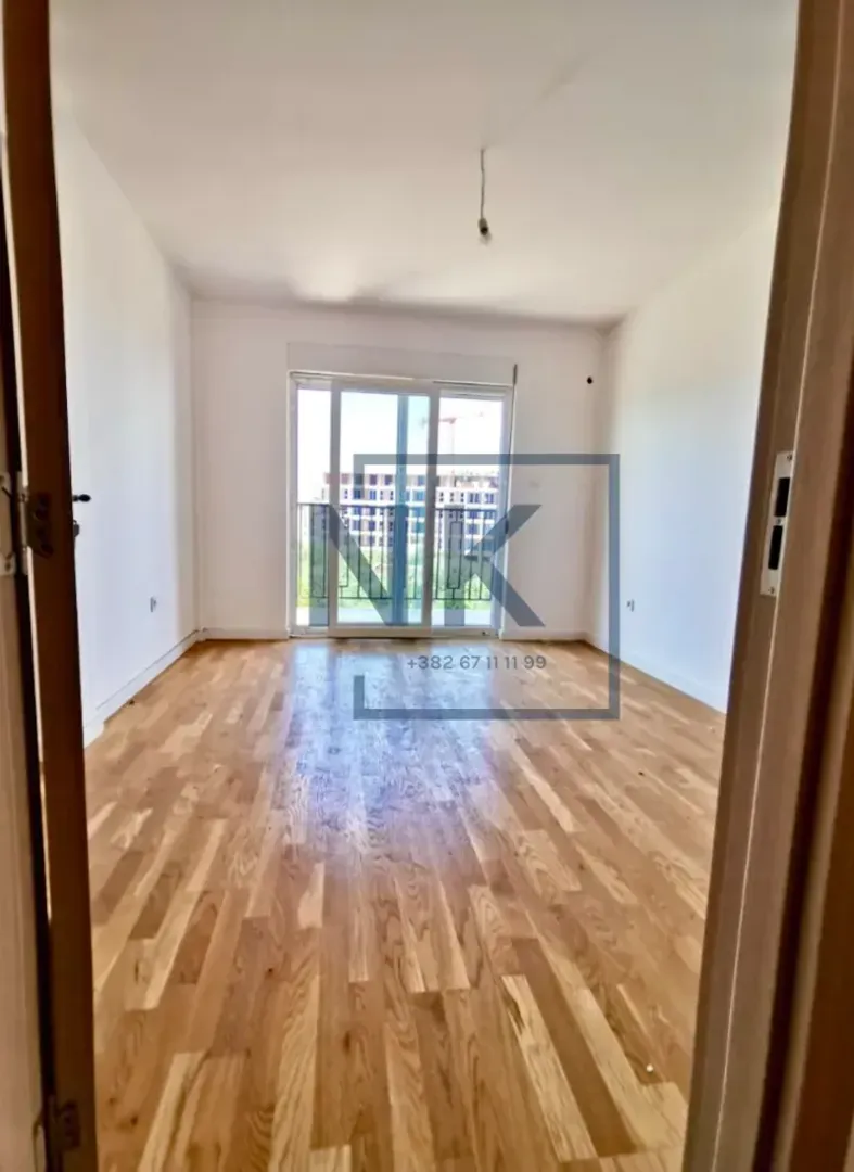 Empty room with hardwood flooring and balcony doors.