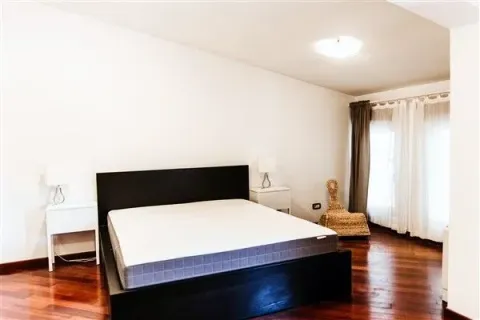 Bright bedroom with a dark double bed and wooden flooring. - image 19