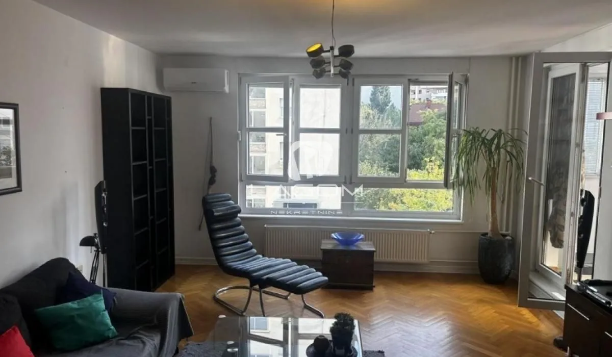 Living room with furniture, a bookcase and a large window.