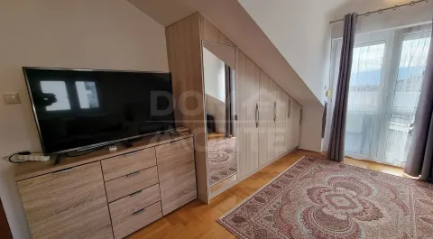 Potkrovna spavaća soba sa garderoberom, komodom, televizorom i tepihom. - image 3