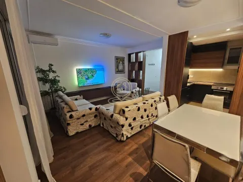 Living room with sofa, TV, dining area, and kitchen in the background. - image 2