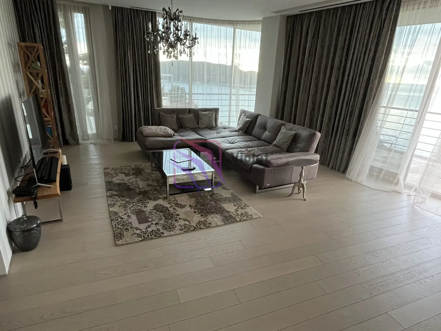 Spacious living room with a sofa, large windows, and a sea view.