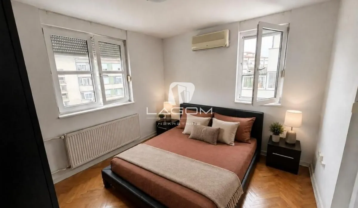 Bedroom with a double bed, bedside tables, and two windows.