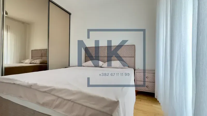 Furnished bedroom with a double bed, mirrored wardrobe, and nightstand.