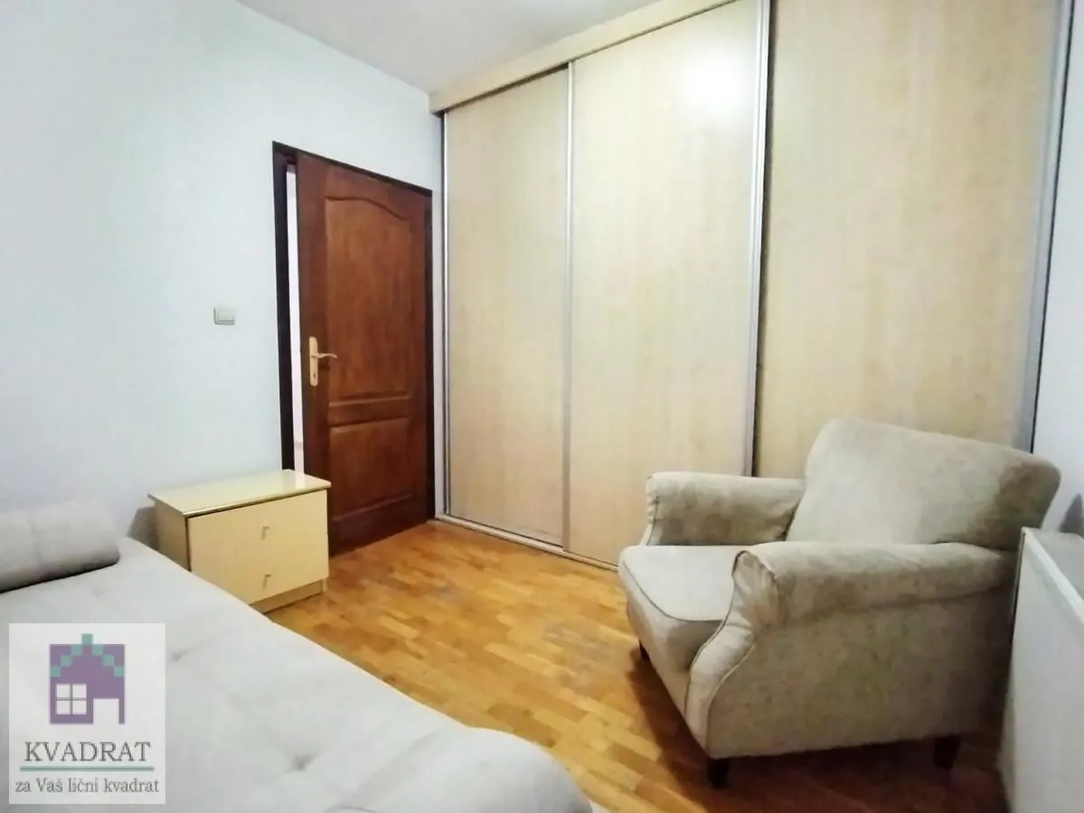 Bedroom with a bed, armchair, built-in wardrobe, and wooden door.
