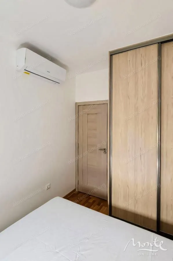 Spavaća soba sa krevetom, ugradnim plakarom i klima-uređajem na zidu.