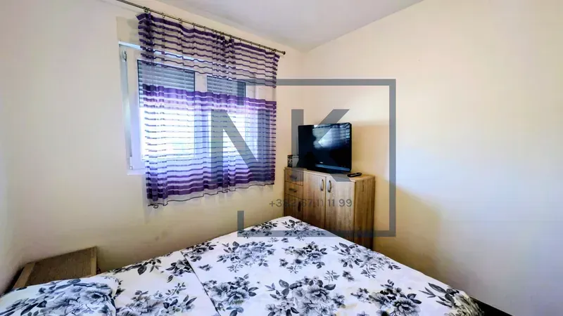 Furnished bedroom with a double bed and a television.