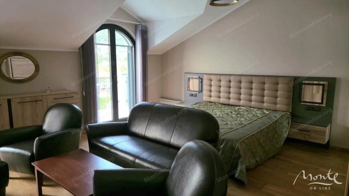 Prostrana spavaća soba sa bračnim krevetom, garniturom za sjedenje i balkonskim vratima.