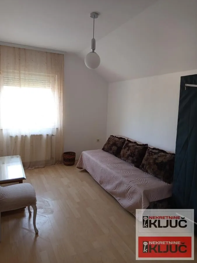 Manja dnevna soba sa kaučem i prozorom.