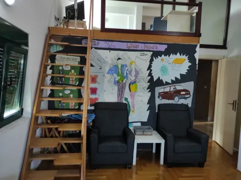Living room with two armchairs, wooden stairs leading to a loft, and a painted mural on the wall. - image 13