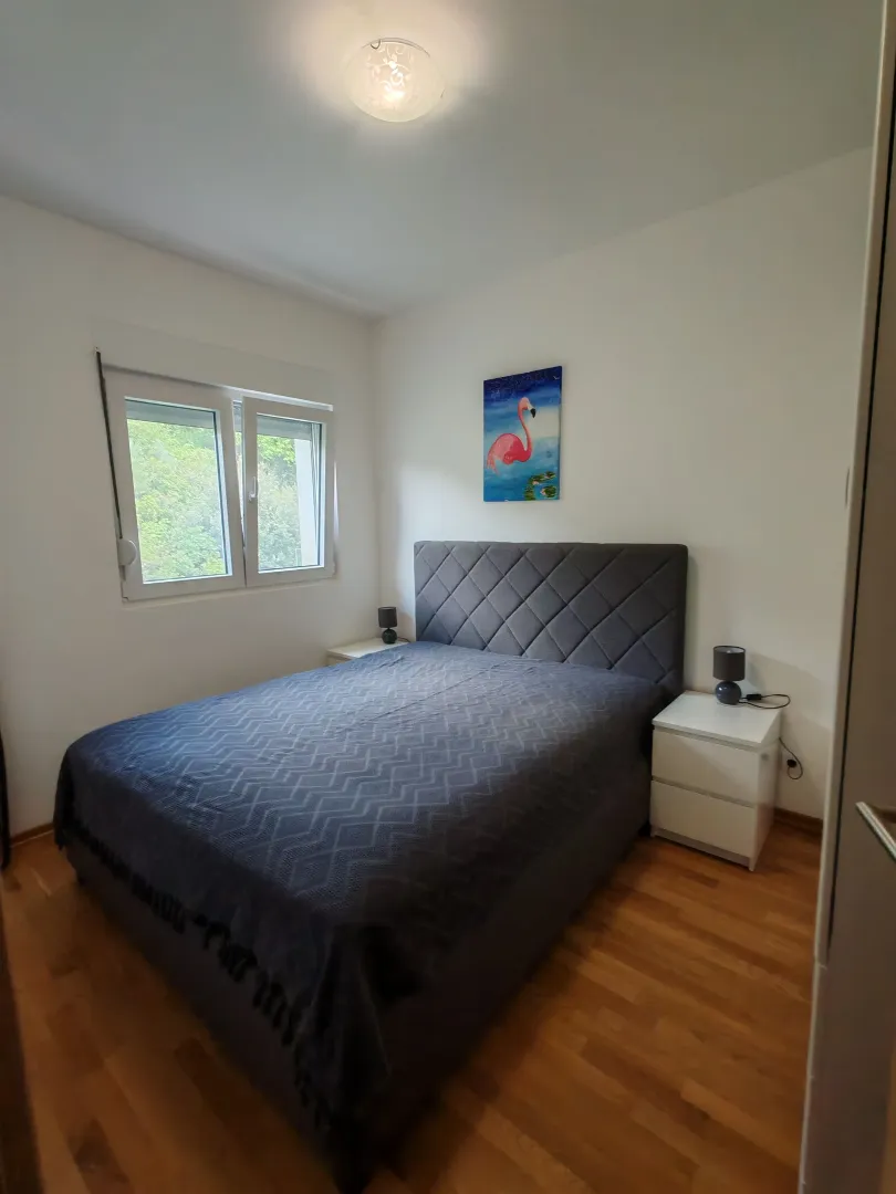 Bright bedroom with a double bed, white nightstands, and a window.