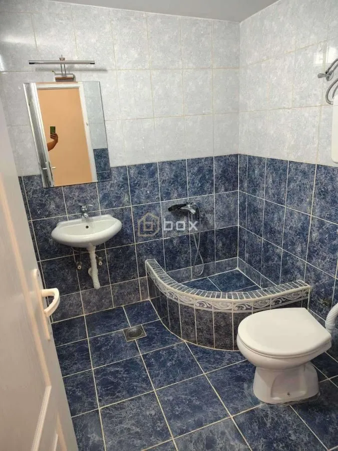 Smaller tiled bathroom with a sink, shower cabin, and toilet.
