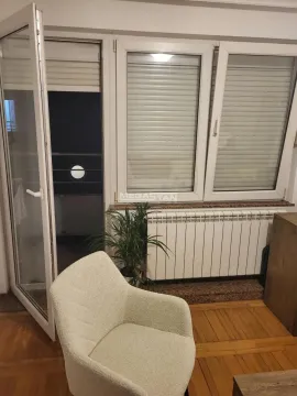 View of the windows and balcony door with an armchair in the living room. - image 2