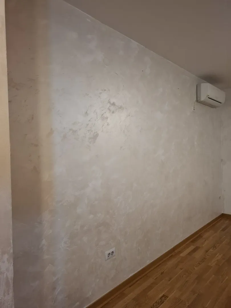 Prazan zid sa dekorativnom tehnikom i klima uređajem u neopremljenoj prostoriji.
