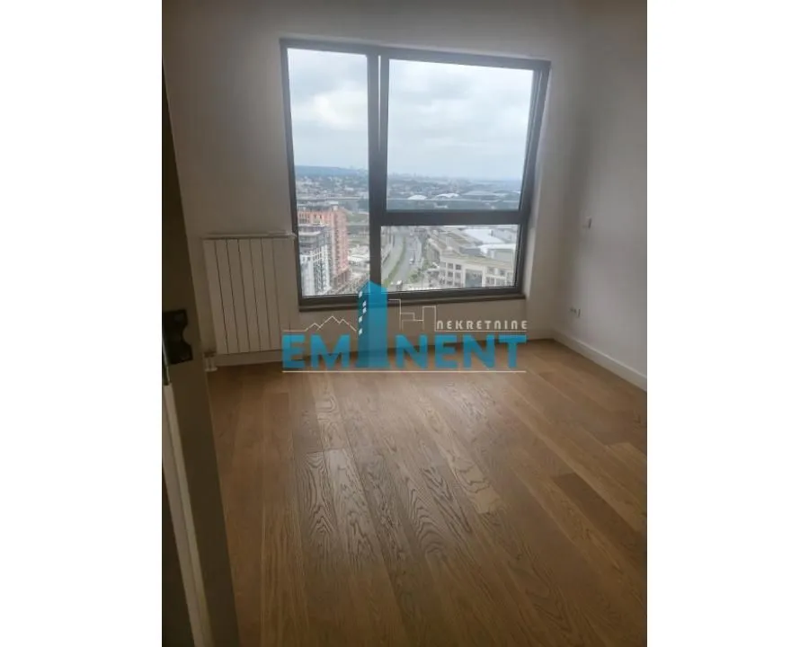 Empty room with wooden flooring and a large window overlooking the city.