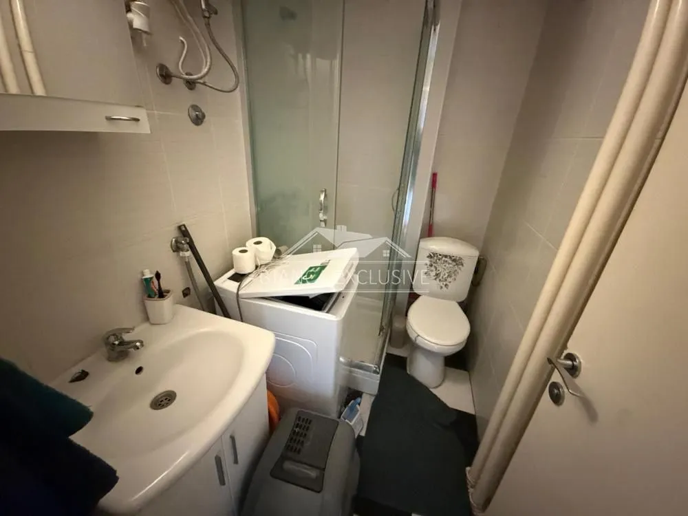 Small bathroom with a sink, toilet, shower cabin, and washing machine.