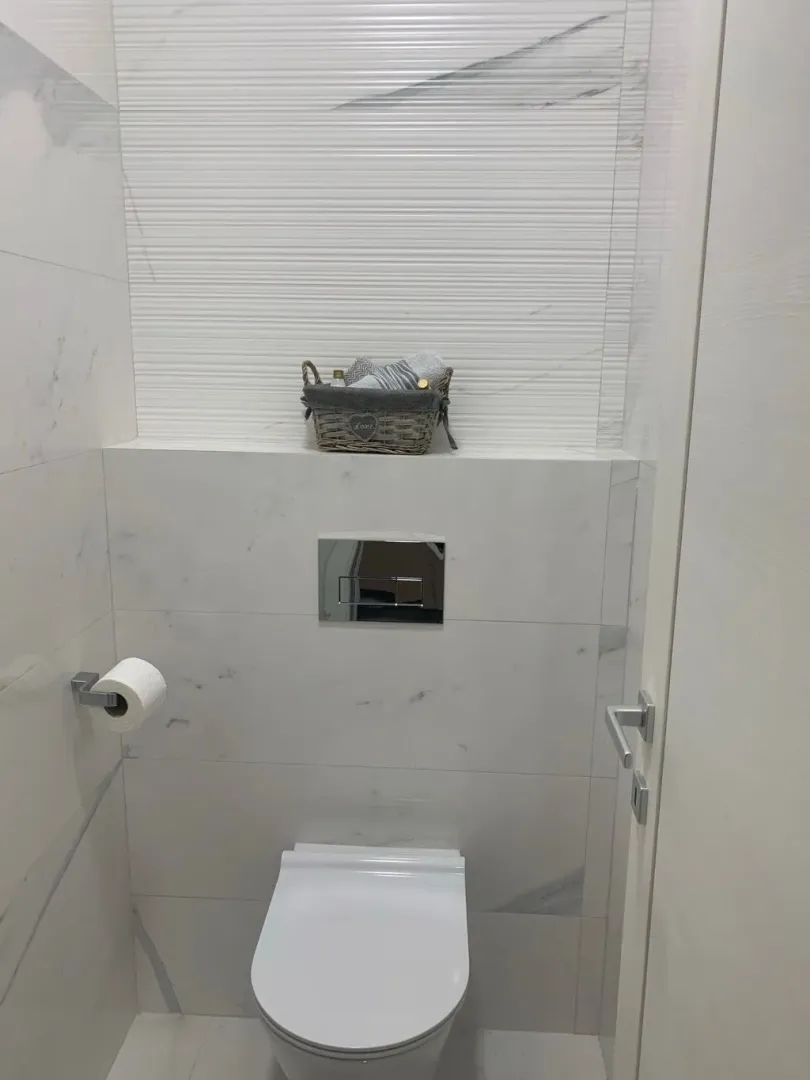 Moderne kupatilo sa bijelim pločicama i ugradnom šoljom.