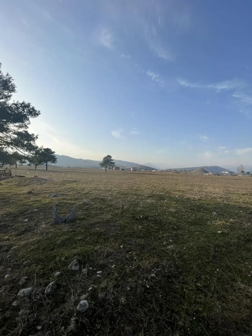 Prostran plac sa travnatom površinom pod plavim nebom.