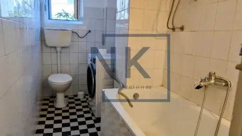 Small bathroom with a bathtub, toilet, and washing machine tiled with ceramic tiles. - image 5