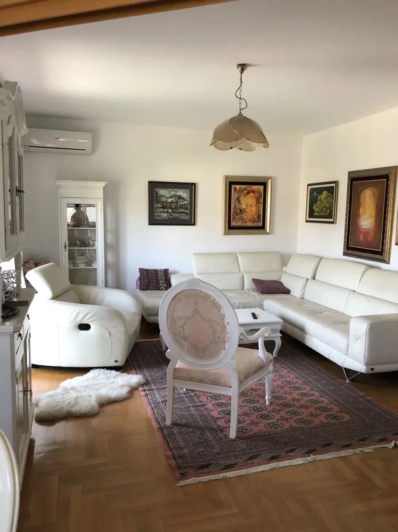Bright living room with a white leather sofa set and paintings on the walls.