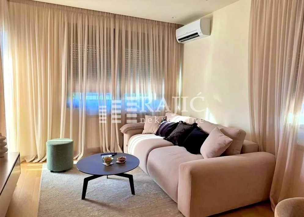 Furnished living room with a sofa and light curtains.