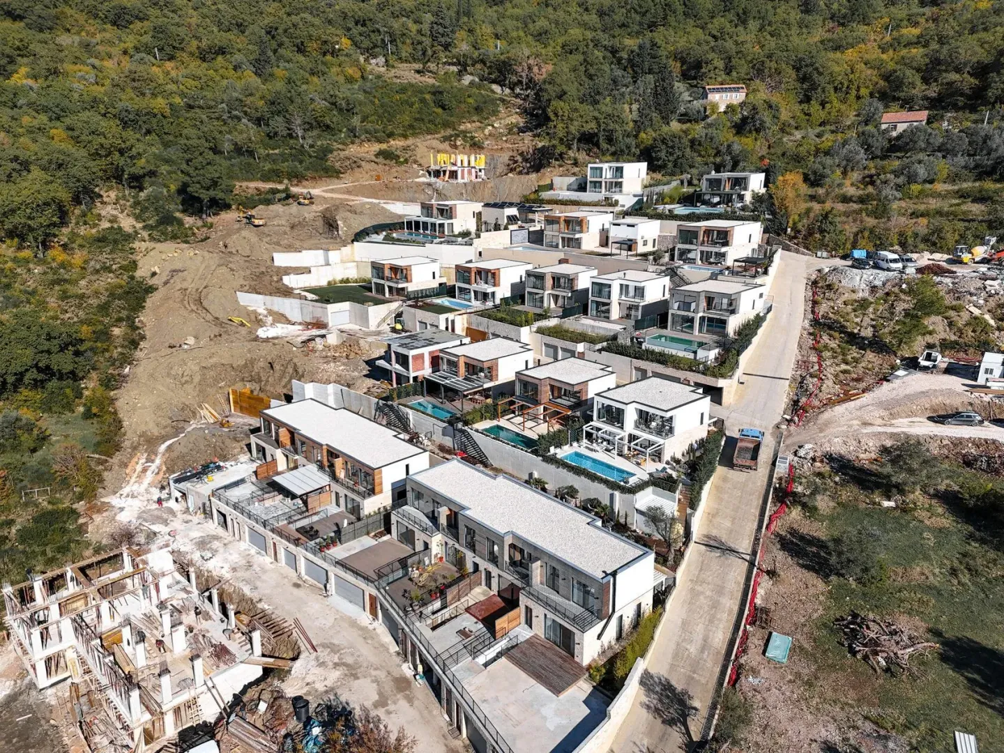 Pogled iz vazduha na kompleks modernih vila u izgradnji na padini.