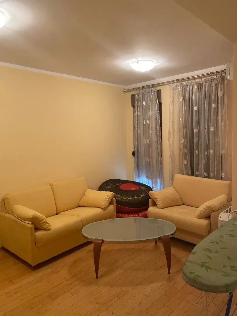 Svijetla dnevna soba sa žutim namještajem i staklenim klub stolom.