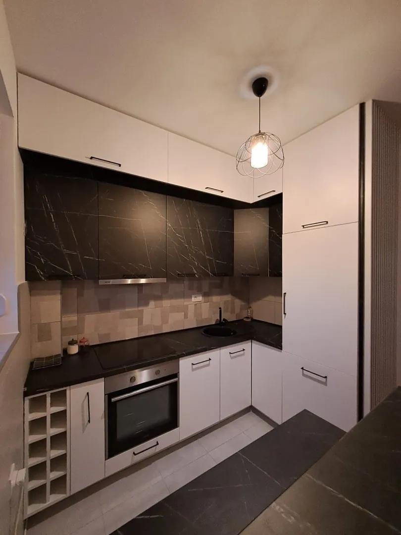 Modern kitchen with black and white cabinets and built-in appliances.