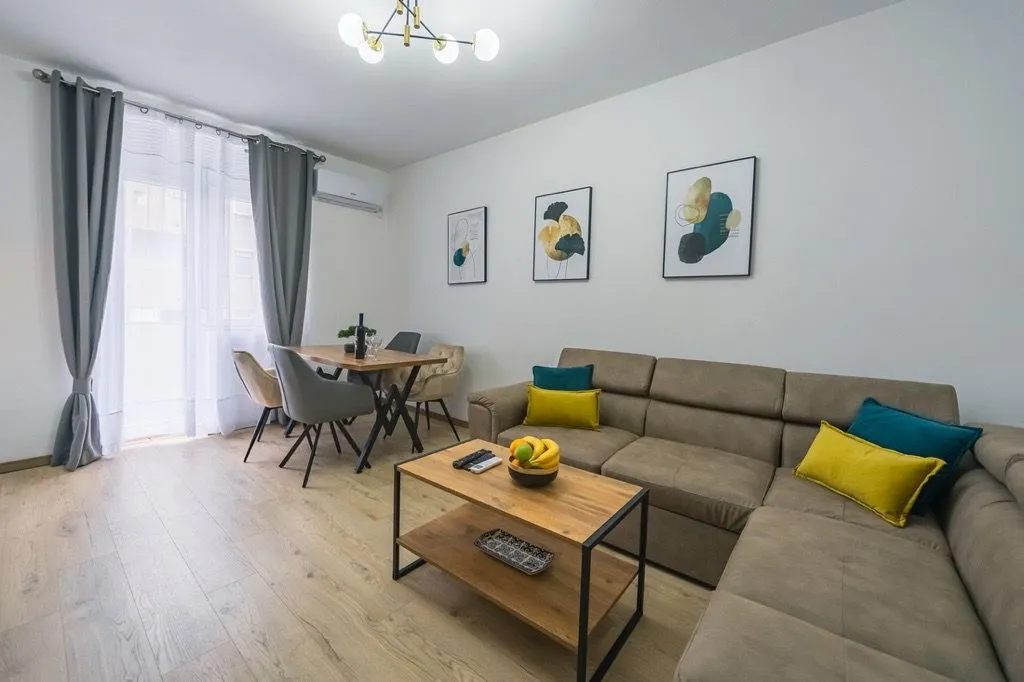 Living room with a sectional sofa, coffee table, and dining area near the window.