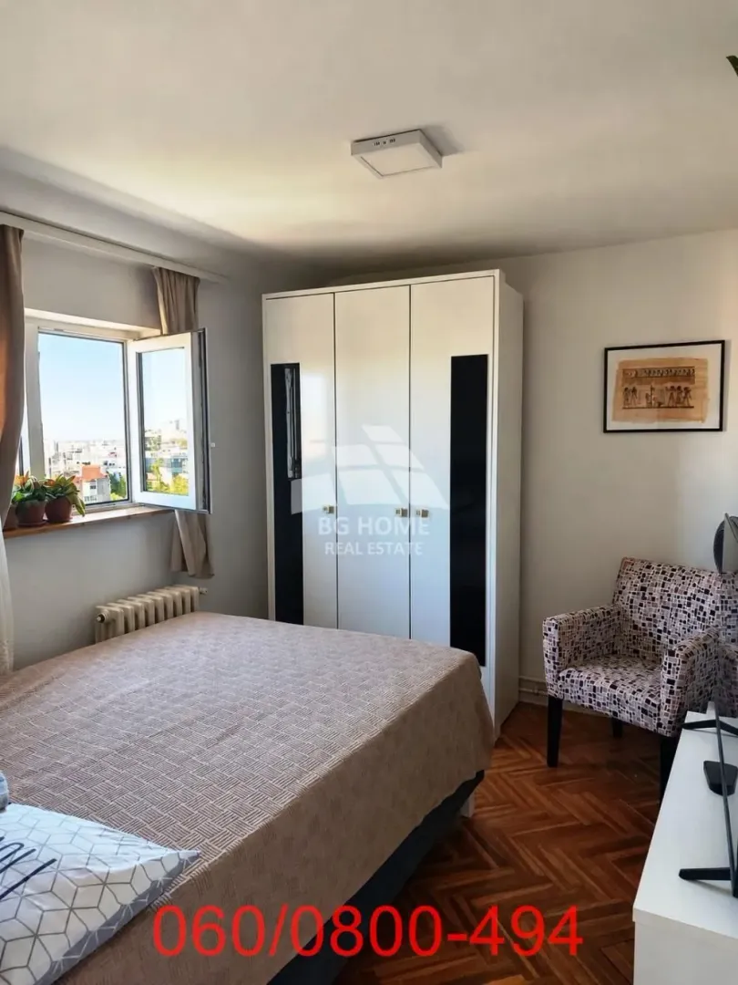Nameštena spavaća soba sa bračnim krevetom, ormarom i foteljom.