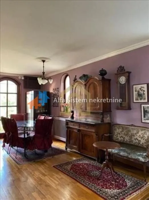 Spacious living room with classic wooden furniture and purple walls.
