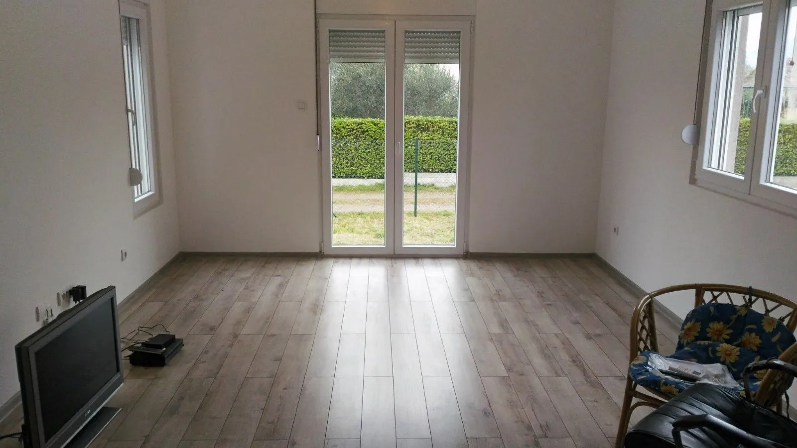 A bright, semi-furnished room with laminate flooring and yard access.