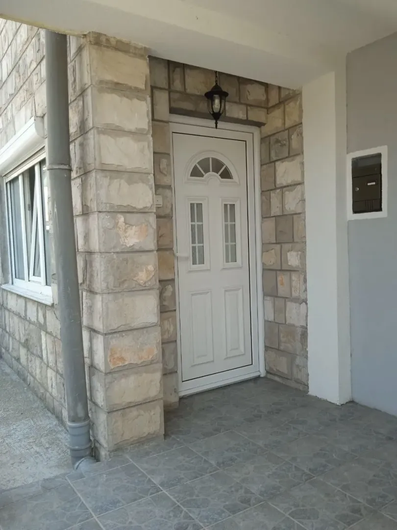 Ulazna vrata kuće obložene kamenom sa tremom.
