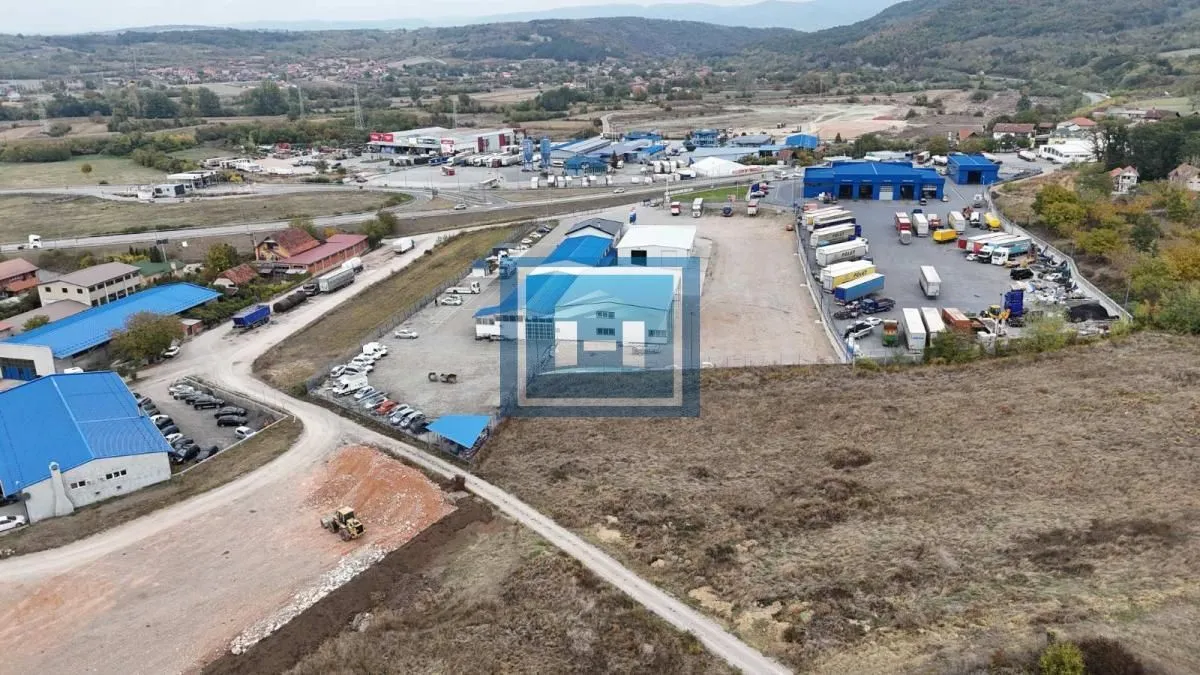 Aerial view of an industrial complex with warehouses and a parking lot for trucks.