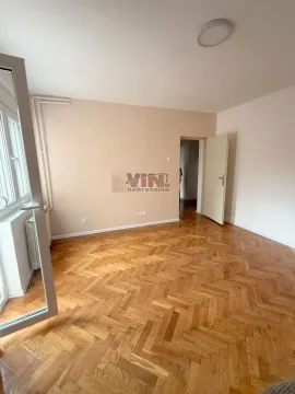 Prazna soba sa drvenim parketom i vratima koja vode u hodnik. - image 3