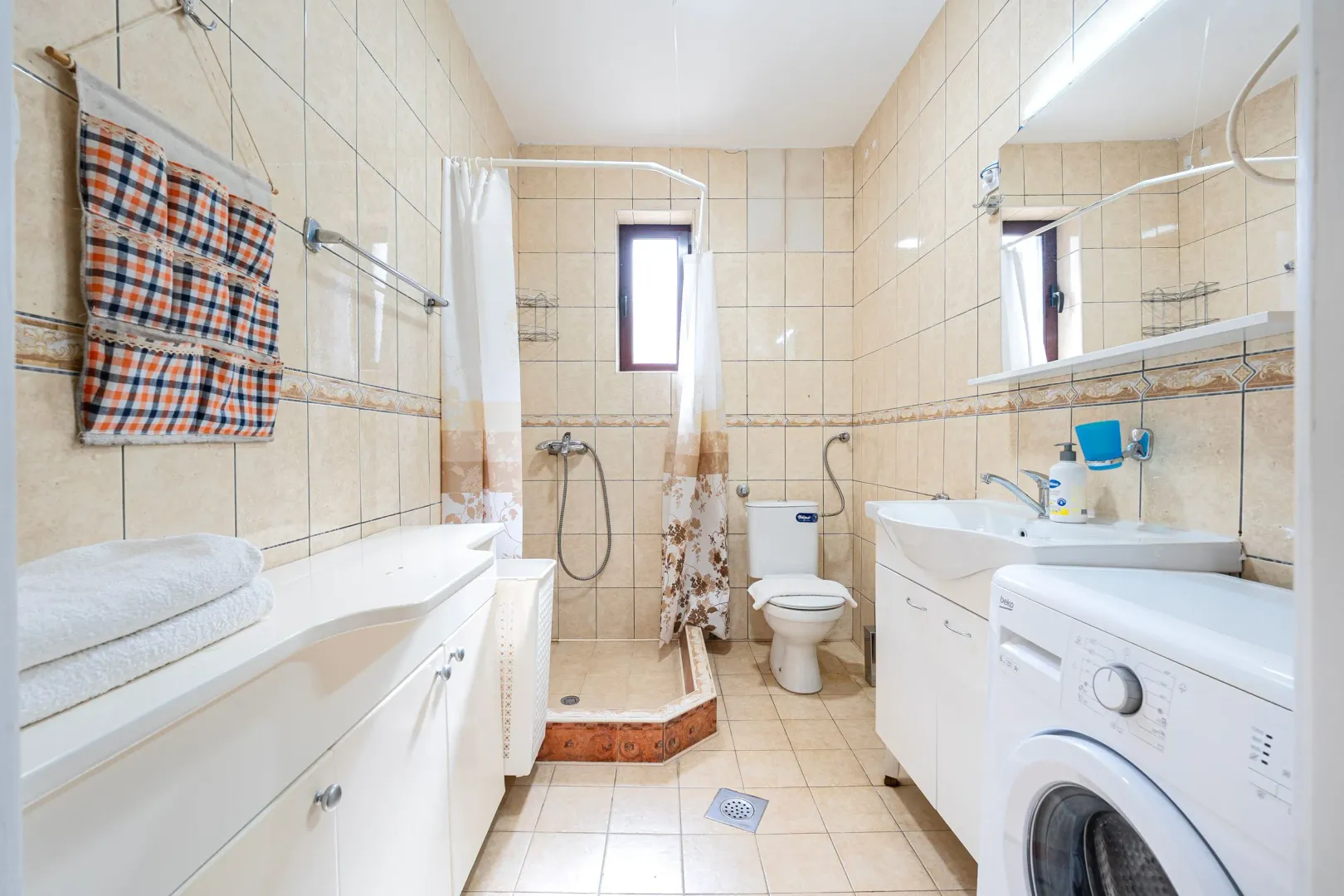 Bathroom equipped with sanitary ware, a shower cabin, and a washing machine.