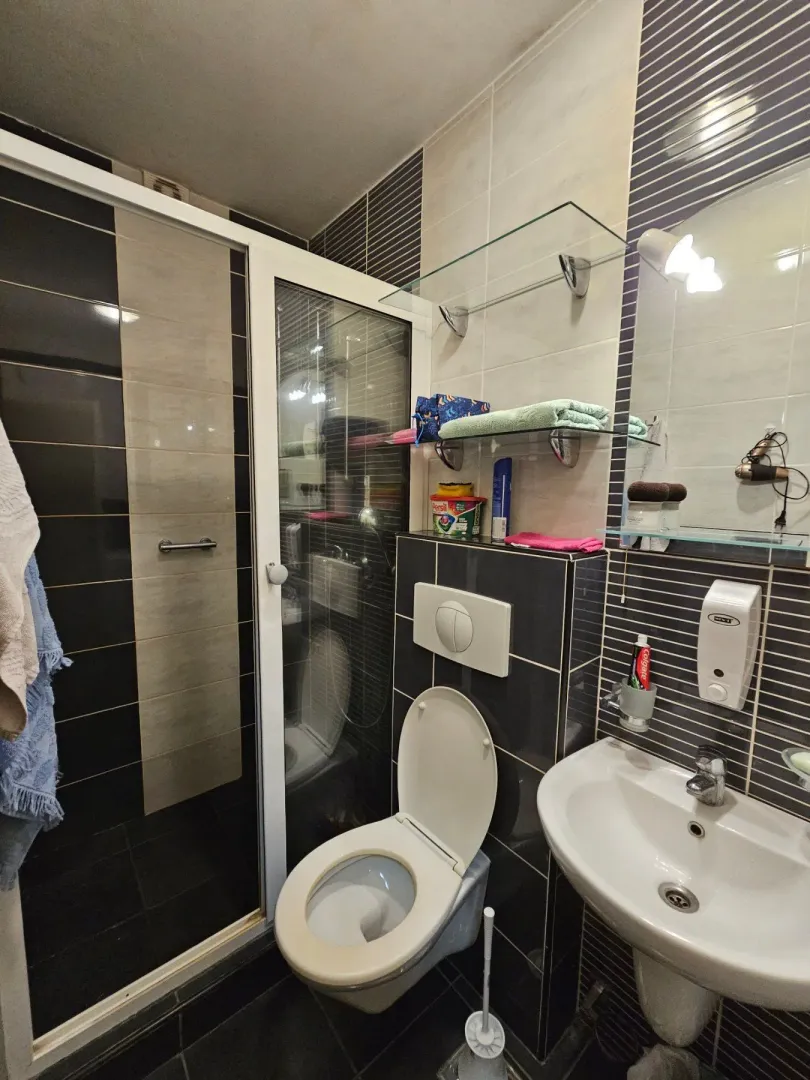 A compact bathroom with a shower cabin, toilet, and washbasin.