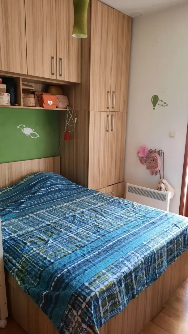Jednostavna spavaća soba sa bračnim krevetom i ugradnim drvenim plakarima.