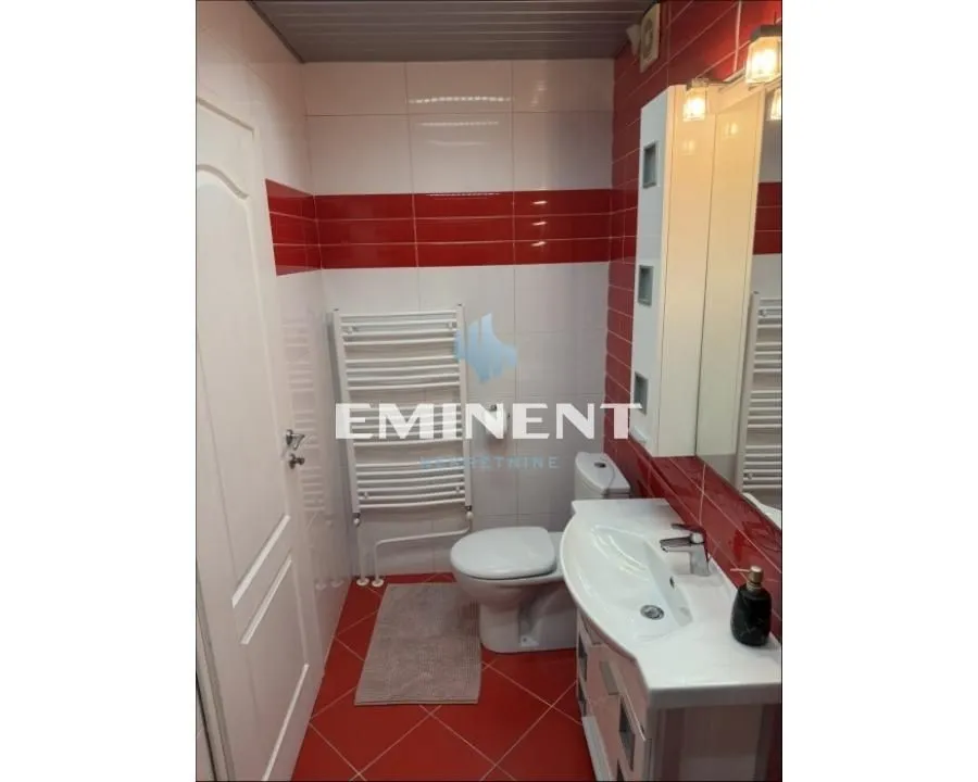 Bathroom with white and red tiles, a vanity, and a toilet.