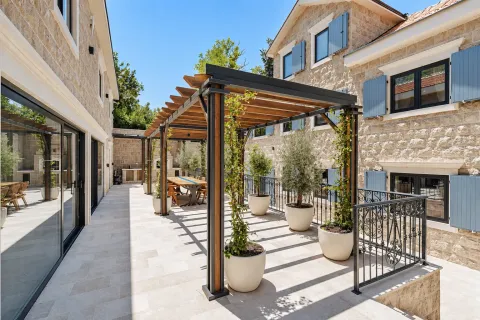 Spacious paved terrace with a pergola and potted olive trees in front of a stone house. - image 19