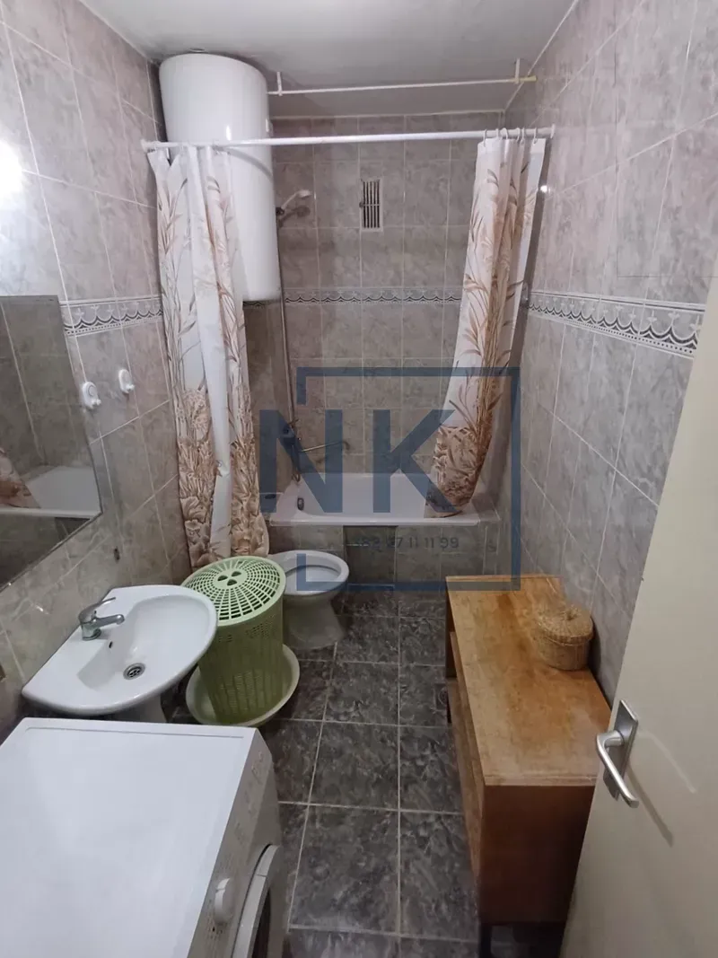 Tiled bathroom with a bathtub, washbasin, and washing machine.
