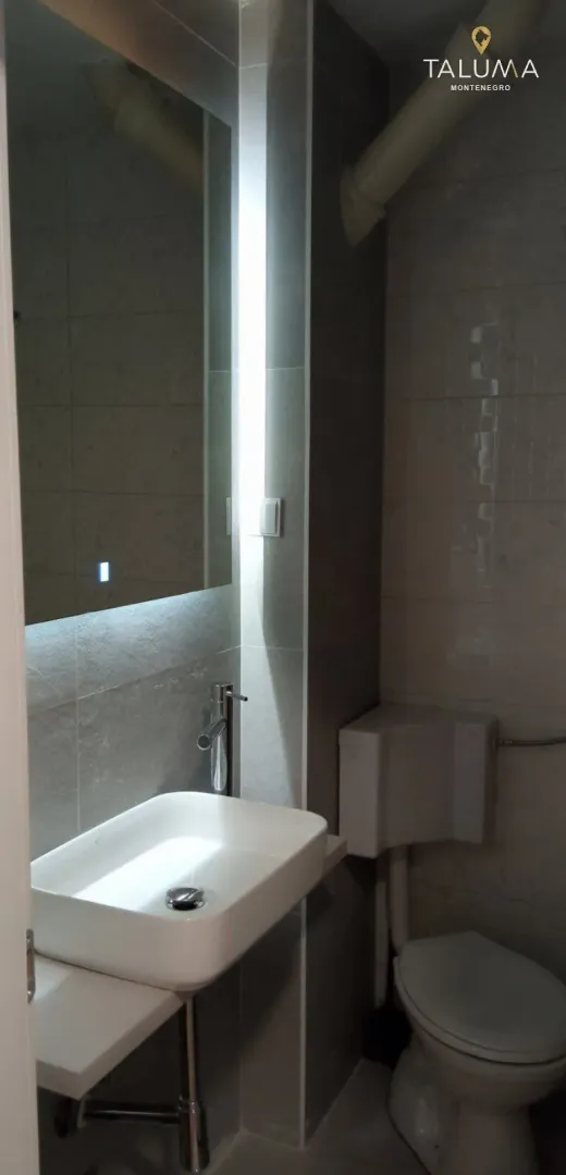 Small bathroom equipped with a sink, toilet, and a large backlit mirror.