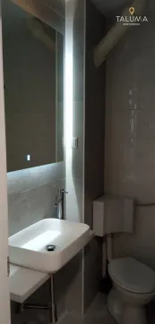 Small bathroom equipped with a sink, toilet, and a large backlit mirror. - image 3