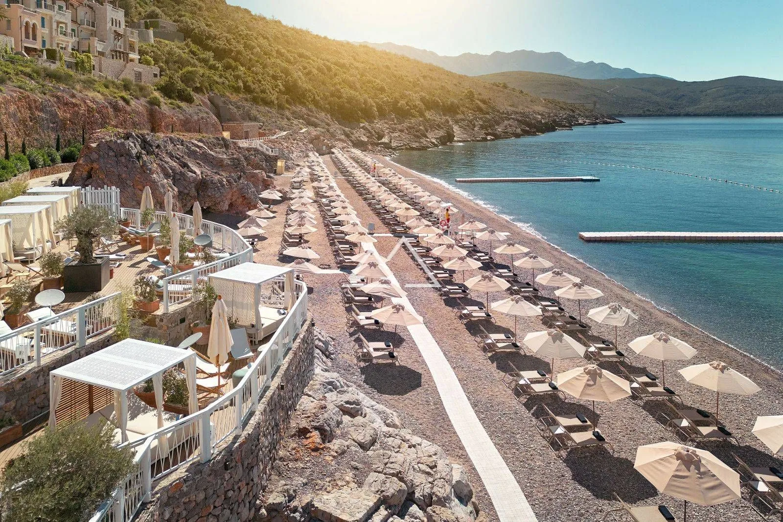 Pogled na uređenu plažu sa ležaljkama i suncobranima pored mora.
