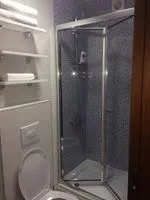 A bathroom with a shower cabin and shelves for towels.