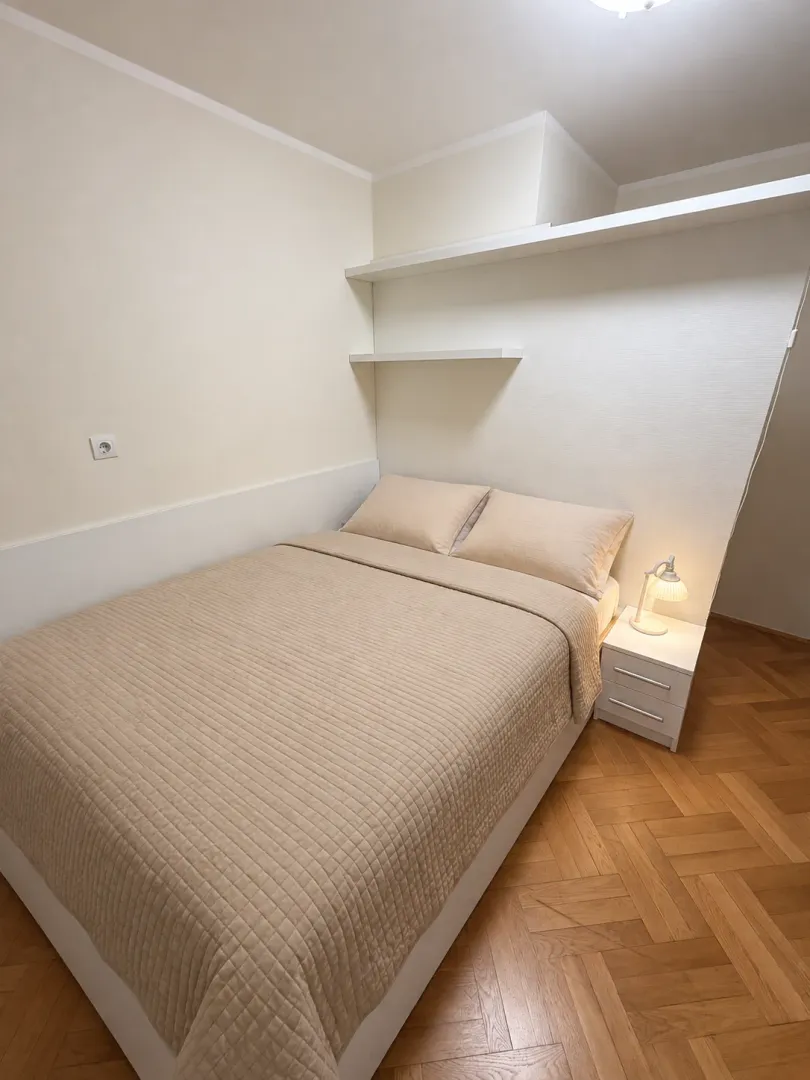 Uređena spavaća soba sa bračnim krevetom i drvenim podom.