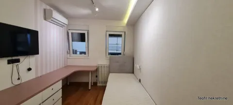 Manja spavaća soba sa krevetom, radnim stolom i televizorom na zidu. - image 10