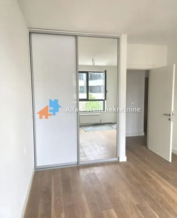 Soba sa ugrađenim plakarom sa ogledalom i drvenim podom.