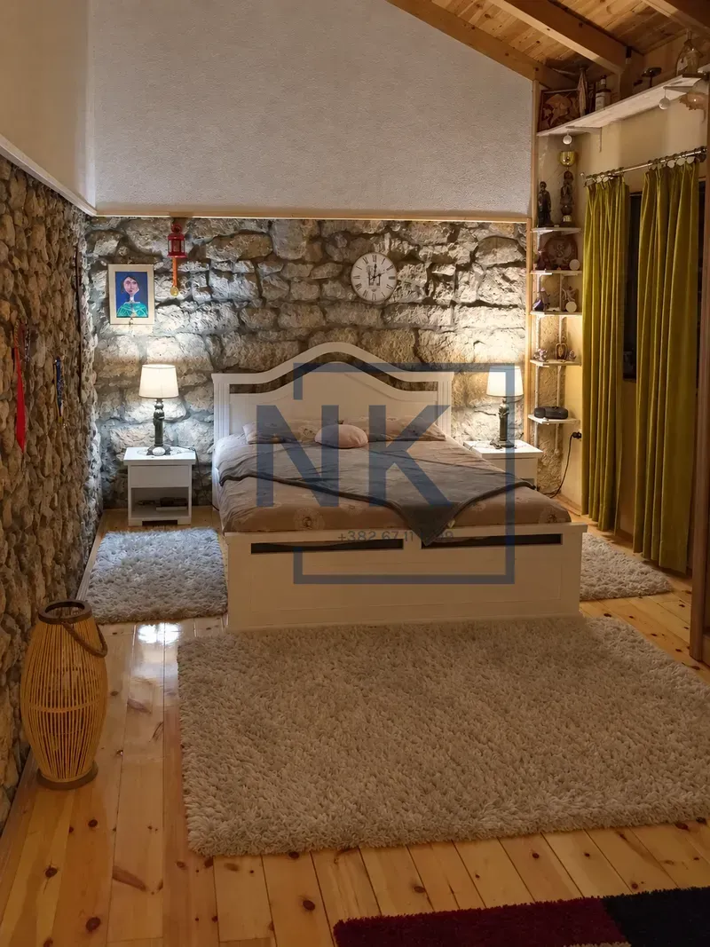 Bedroom with a double bed and a stone wall.